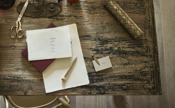 Liste de tâches pour les fêtes de fin d’année et carte de placement sur un bureau en bois brut, une méthode en pleine conscience pour réduire le stress et mieux s’organiser avant le grand jour.